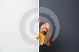 Funny image of a cute baby girl looking behind a copy of the area space. Free space for design