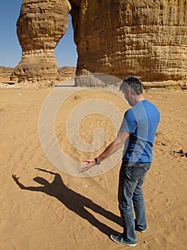 A funny image of a man arguing with his own shadow in front of the Elephant Rock in Saudi Arabia KSA