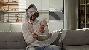 Smiešny indický arabský muž počúvať hudba v slúchadlá na kuchyňa požívať zvuk v predstierať bicie 