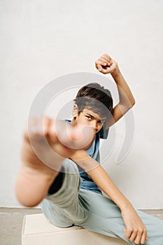 Funny indian boy sitting on a wooden box, touching camera lenz with his foot