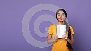 Funny indian lady holding pen as moustache over purple background