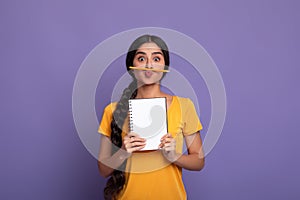 Funny indian lady holding pen as moustache over purple wall