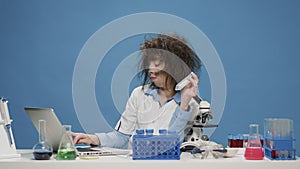 Funny insane female scientist looking at test tubes on desk