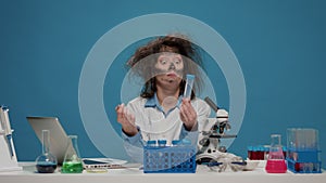 Funny insane female scientist looking at test tubes on desk