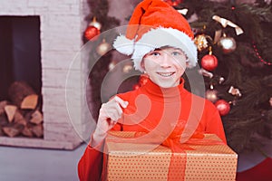 Funny kid boy holding christmas gift in room