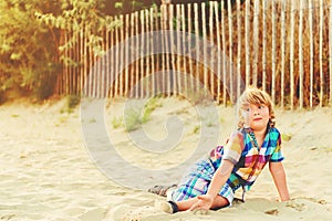 Funny kid boy resting on sand beach