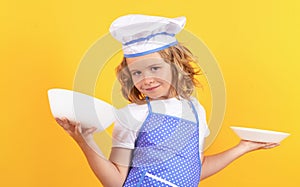 Funny kid chef cook with kitchen plate, studio portrait. Kid chef cook, studio portrait. Children cooking. Kid boy with