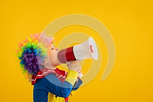 Funny kid clown playing against yellow background