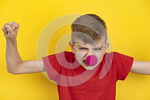 Funny kid clown on yellow background. Teen poses angry face