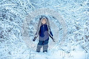 Funny kid coming to the winter forest on snow landscape. Joyful child Having Fun in Winter Park. Cute toddler boy