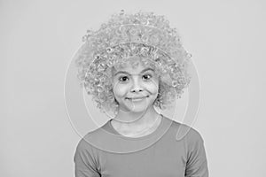 Funny kid in curly redhead wig. Time to have fun. Teen girl with orange hair, being a clown. Happy teenager portrait