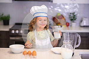 Funny kid with eggs at kitchen. Children cooking in the kitchen. Funny kid chef cook cookery at kitchen. Chef kid boy