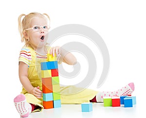 Funny kid in eyeglases making tower using blocks
