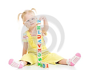 Funny kid in eyeglases making tower using blocks