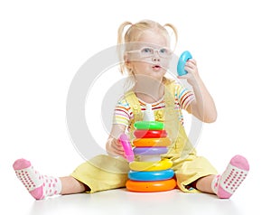 Funny kid in eyeglases playing colorful pyramid photo