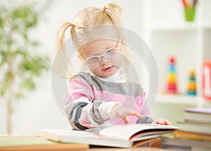 Funny kid in eyeglases reading book at home photo