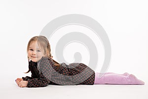 Funny kid female in dress lloking at the camera, redhead girl lies on the ground isolated over white background photo
