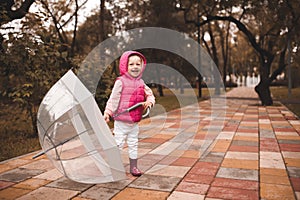 Funny kid girl 4-5 year old wear rainboots and raincoat walk in puddler outdoors close up. Autumn season concept