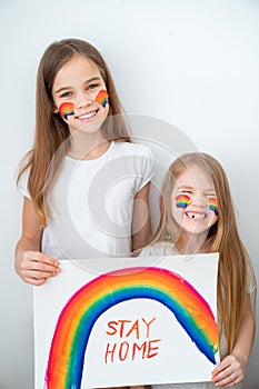 Funny kid girls drew rainbow and poster stay home. photo