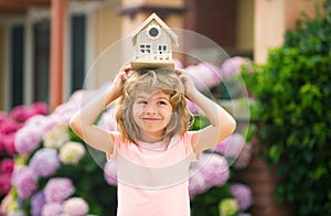 Funny kid hold toy little house. Child making a new dream home. Family home dream. Adorable child with toy wooden house