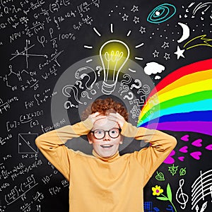 Funny kid. How do I choose the right career path? Child student boy with science and art pattern on blackboard background