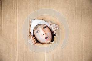 Funny kid looking through hole on cardboard