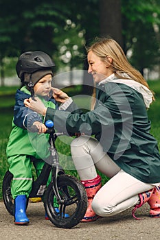 Funny kid in rain boots playing in a rain park