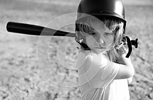 Funny kid up to bat at a baseball game. Close up child portrait.