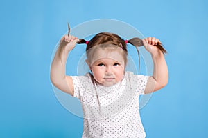 Funny kid in white T-shirt on blue background. Little pretty girl isolated on blue background. Copy space for text.