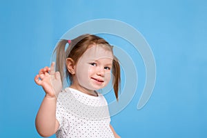 Funny kid in white T-shirt on blue background. Little pretty girl isolated on blue background. Copy space for text.