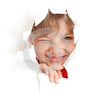 Funny kid wink eye in torn paper hole isolated