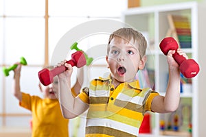 Funny kids boys exercising with dumbbells at home. Healthy life, sportive children.