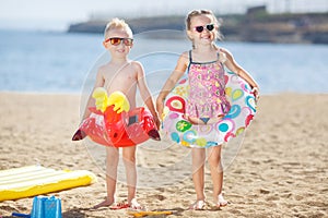 Funny kids with colorful buoys on the beach