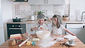 Funny kids cooking together. Boy is breaking eggs. Brother and sister in the kitchen. Children are cooking