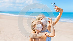 Funny kids in face masks taking selfie photo on beach