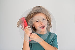 Funny kids hairstyle. Cute child with comb. Blonde kid combs unruly hair. Kid boy with tangled long hair.