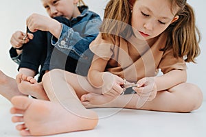 Funny kids. Little siblings with bare feet clipping their fingernails.