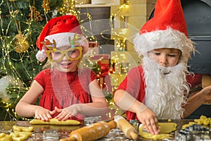 Funny kids are preparing the dough playing with flour in the kitchen. Funny children are preparing gingerbread for