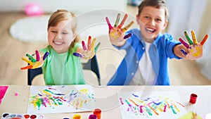 Funny kids show their palms the painted paint. creative classes fine arts. two children a boy and a girl laugh. selective focusing photo