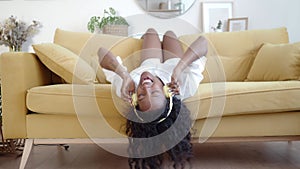 Funny latin american young woman lying on sofa listening to music