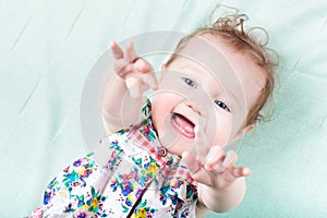 Funny laughing baby girl playing on a green blanket