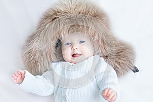 Funny laughing baby girl wearing huge winter hat