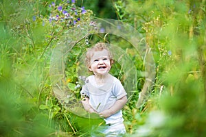 Funny laughing baby in a green summer field