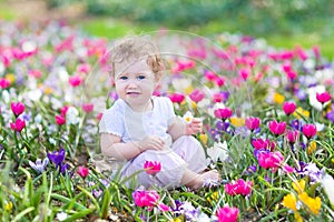 Funny laughing baby playing with first spring flowers
