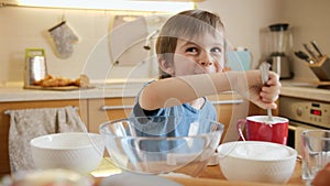 Funny laughing little boy eating creme for baking pie with spoon. Children cooking with parents, little chef, family