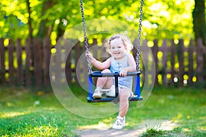 Funny laughing toddler girl swinging ride on playground