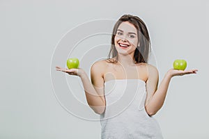 Funny laughing woman holding two green apples in her eyes. White background of a healthy eating concept. Diet