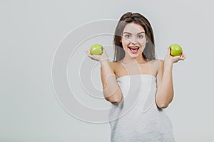 Funny laughing woman holding two green apples in her eyes. White background of a healthy eating concept. Diet