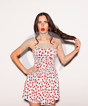 Funny lifestyle portrait of crazy girl, emotional and happy mood, having fun, chic clothes and summer dress. Indoors.