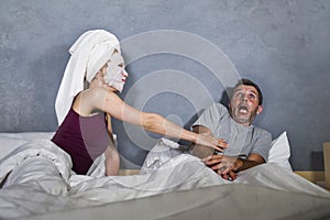 Funny lifestyle portrait of man and woman featuring weird married couple with wife in head towel and makeup face mask demanding se